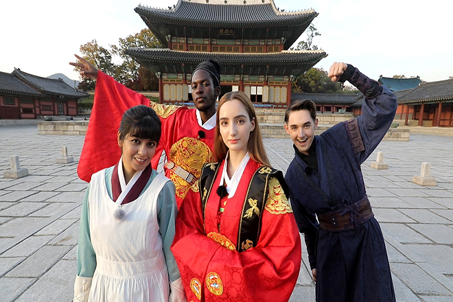 A picture of foreigners standing in front of the palace wearing traditional Korean clothes.